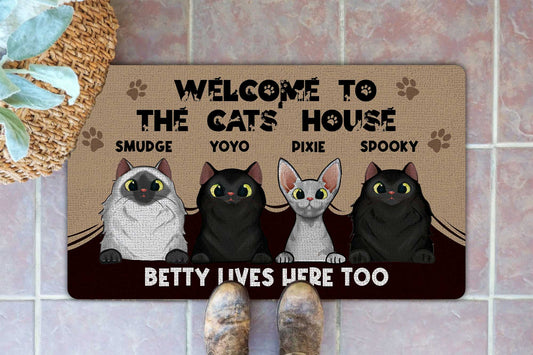 Doormat with cartoon cats and text 'Welcome to the cats house' on a tiled floor.