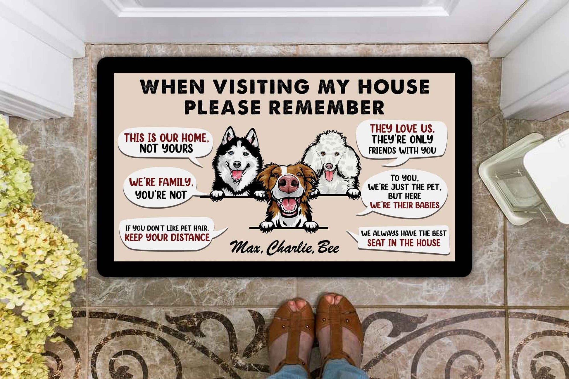 Doormat with cartoon dogs and humorous text on a tiled floor.