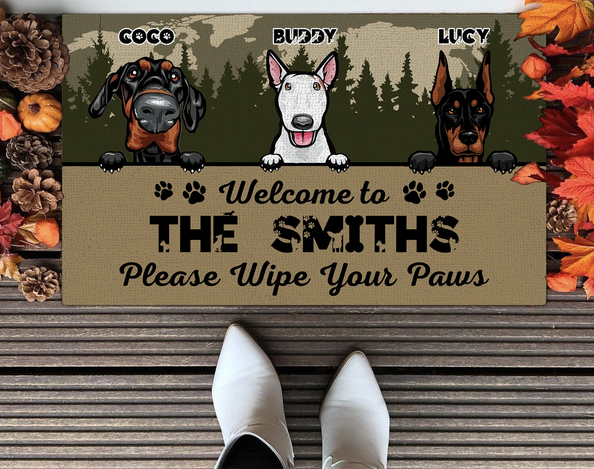 Doormat with three dog illustrations and personalized text on a wooden floor.