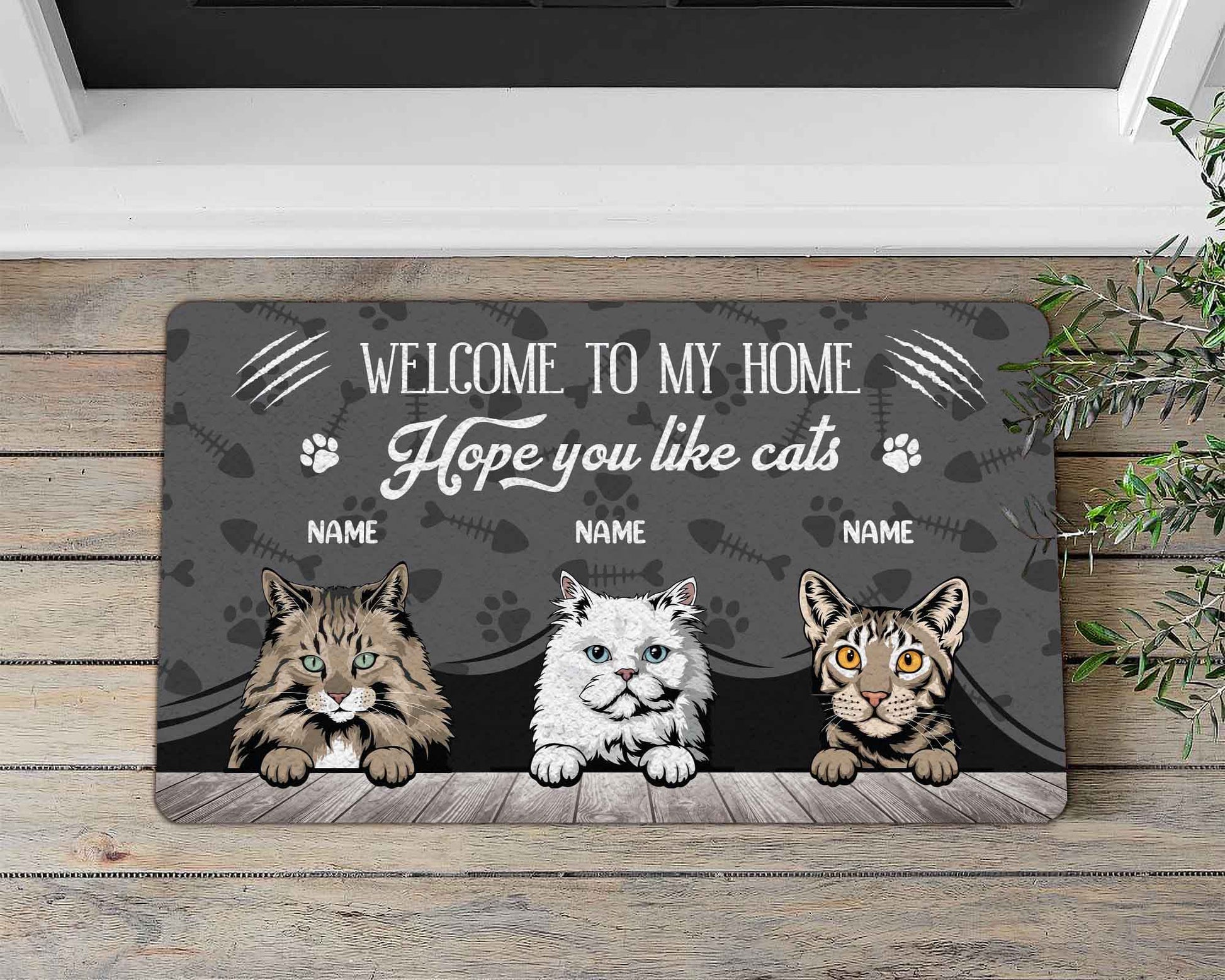 Doormat with three cat illustrations and text on a wooden floor.