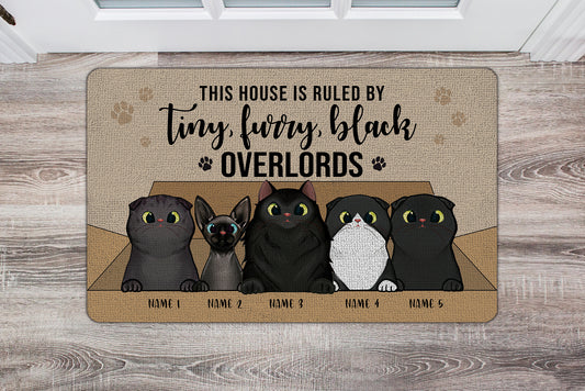Doormat with cartoon cats and humorous text on a wooden floor