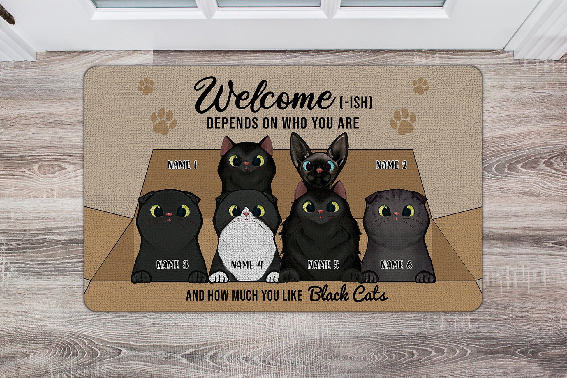 Doormat with cartoon black cats and humorous text on a wooden floor.