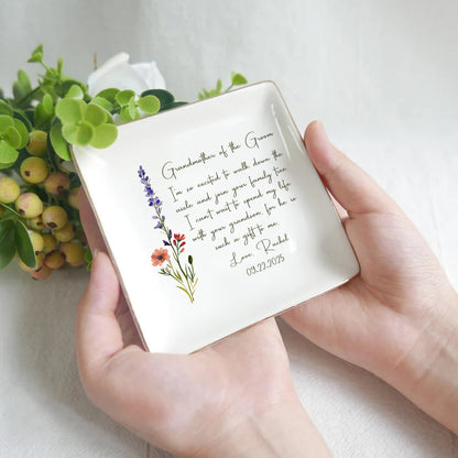Person holding a decorative square plate with floral designs and text on a light background