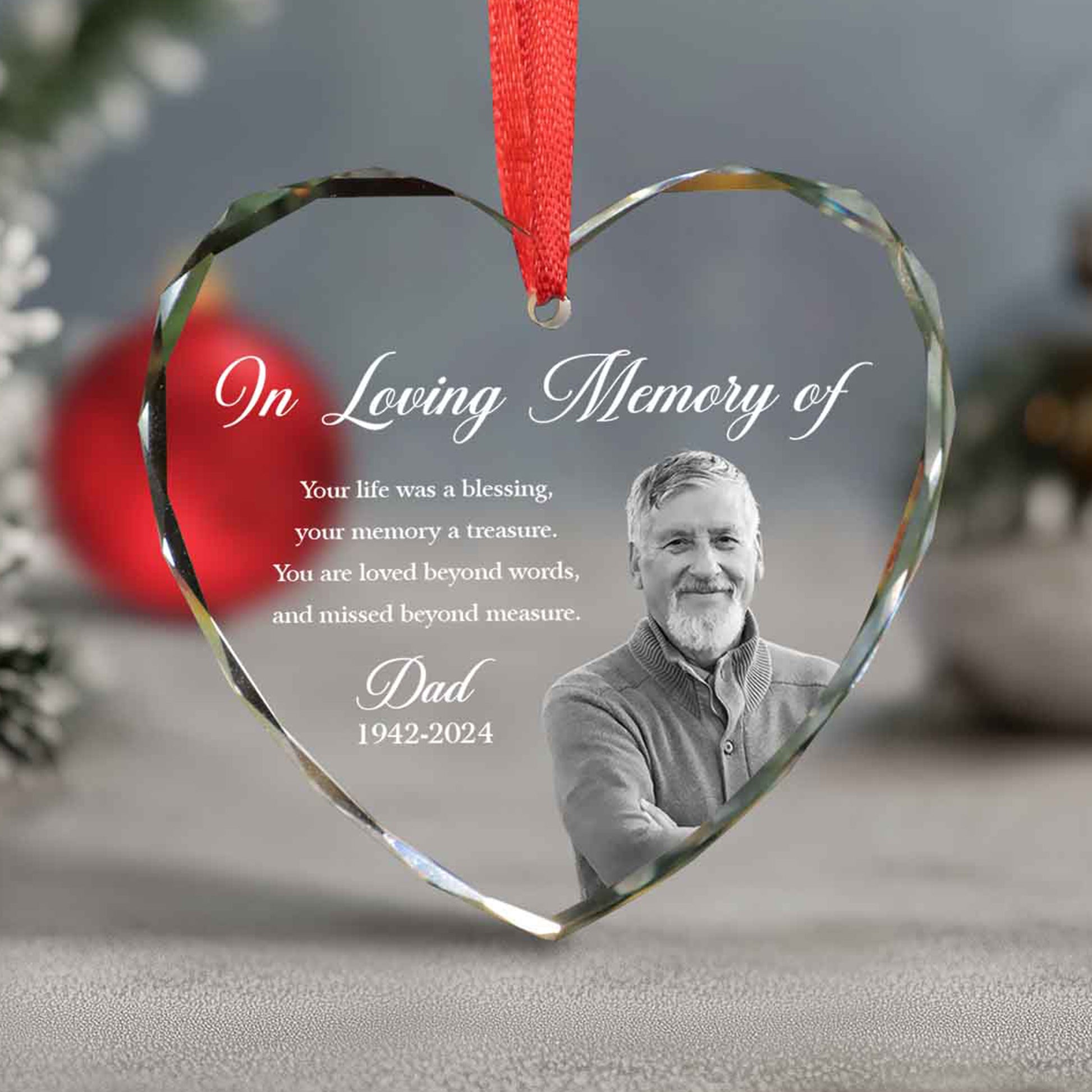 Heart-shaped glass ornament with a photo of a man and text 'In Loving Memory of' on a blurred background.