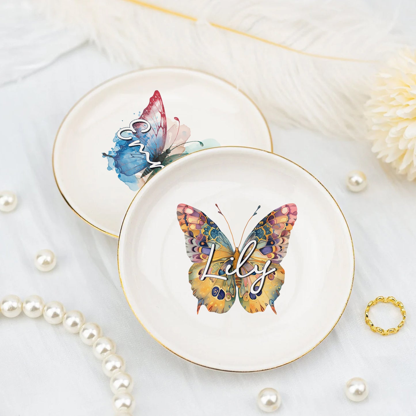 Two decorative plates with butterfly designs and the name 'Lily' on a light background with pearls and a ring.