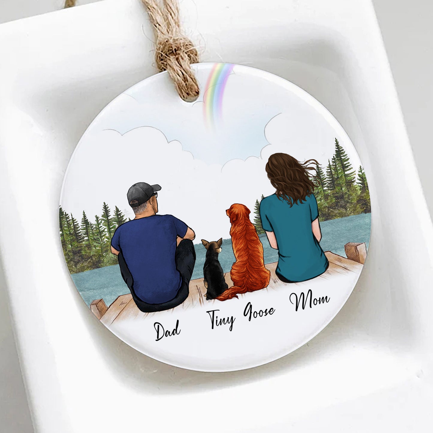 Decorative plate with illustration of a family with two dogs by a lake, on a white background.