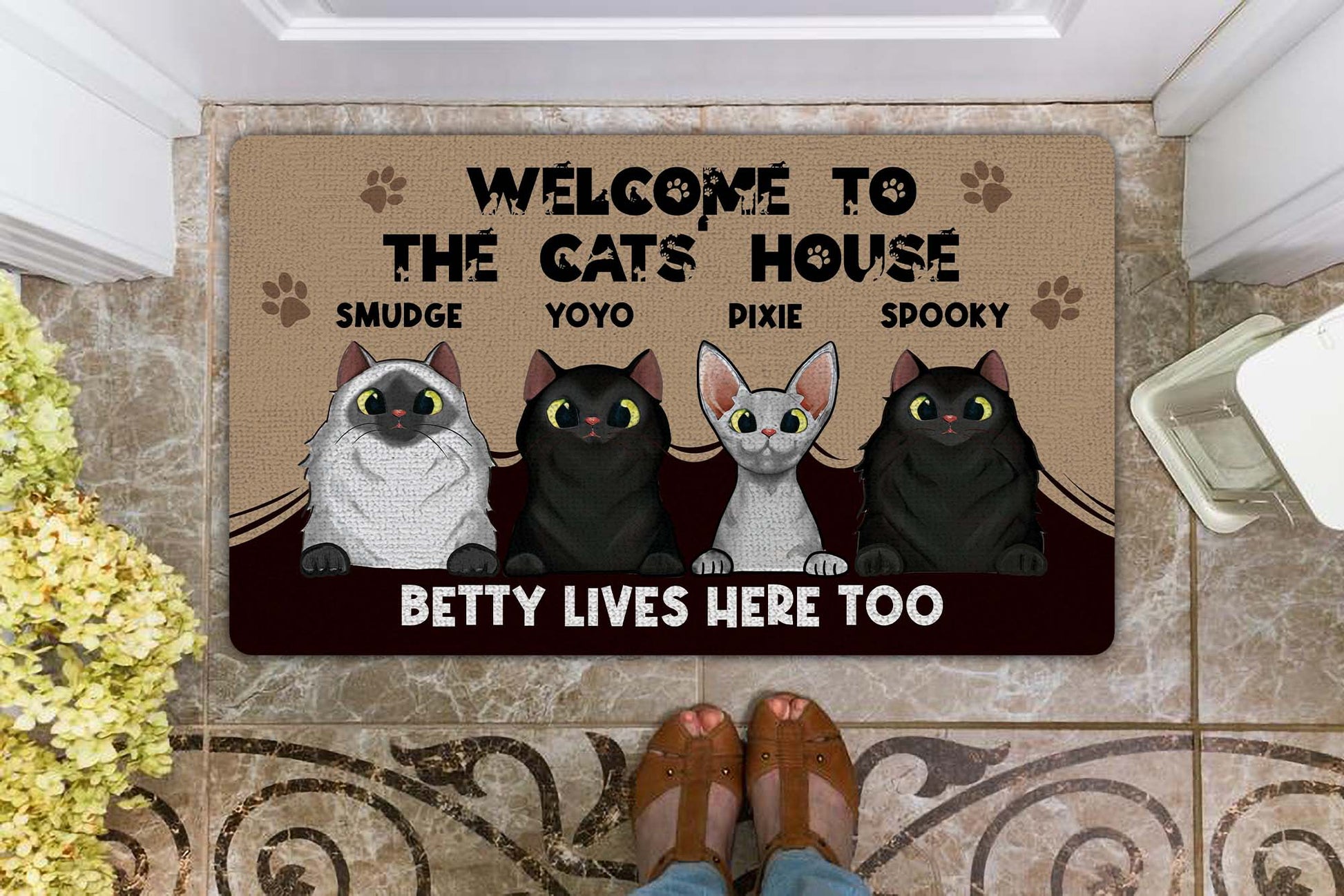 Doormat with cat-themed design and text on a tiled floor.
