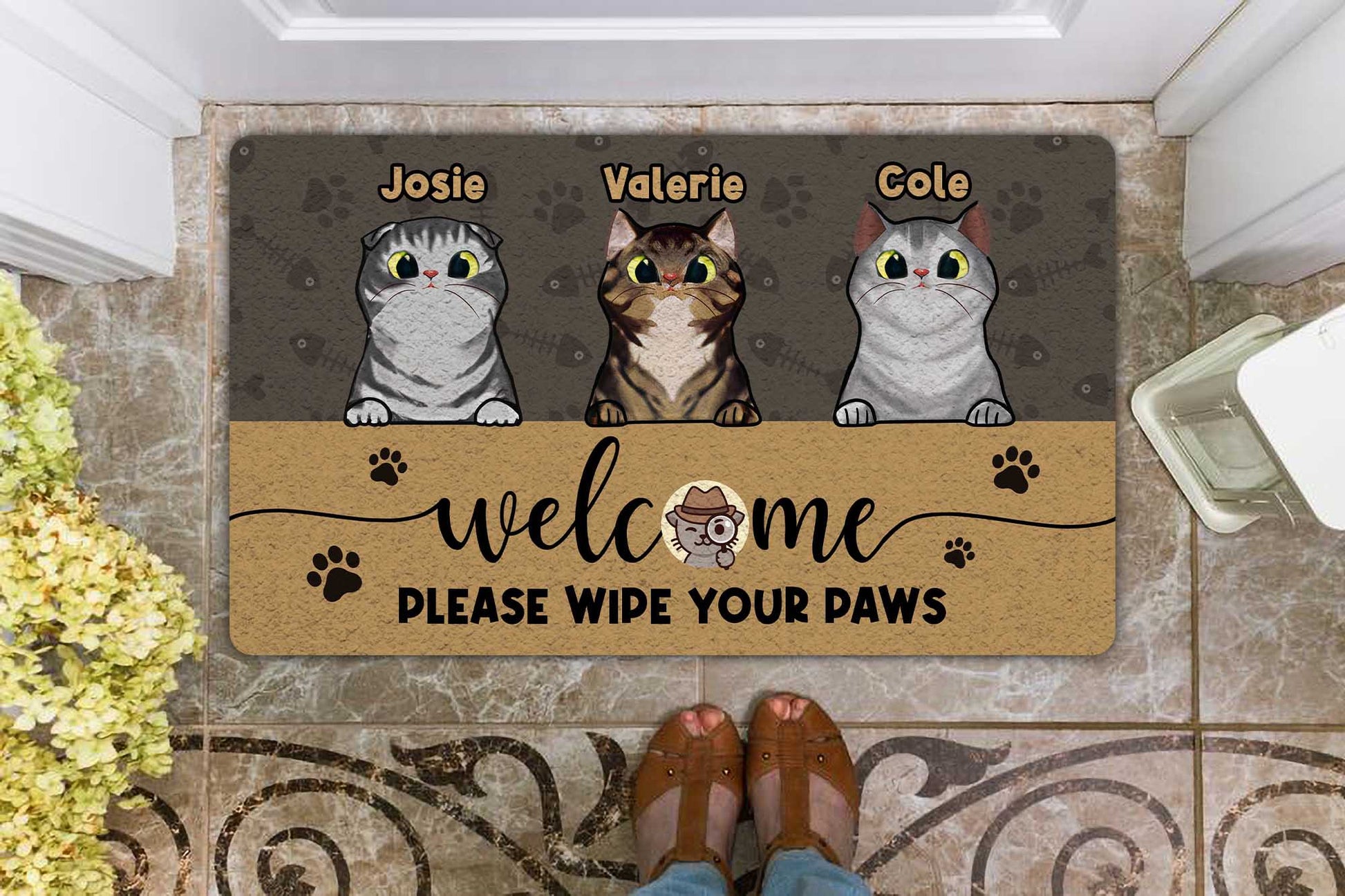 Doormat with three cat illustrations and text on a tiled floor.