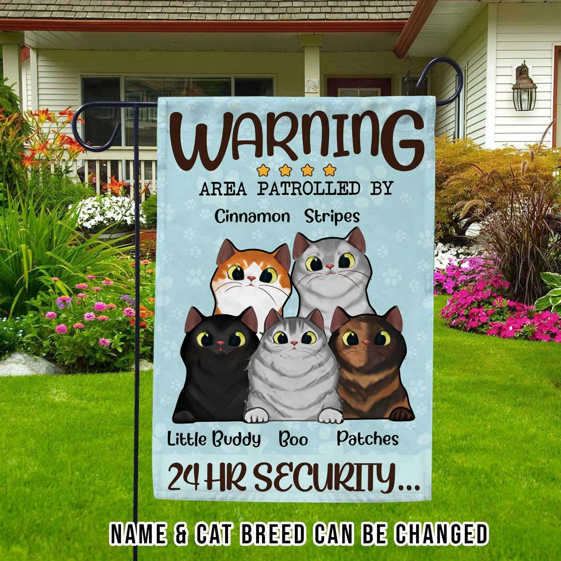 Decorative garden flag with cartoon cats and text about cat patrol, placed outdoors.