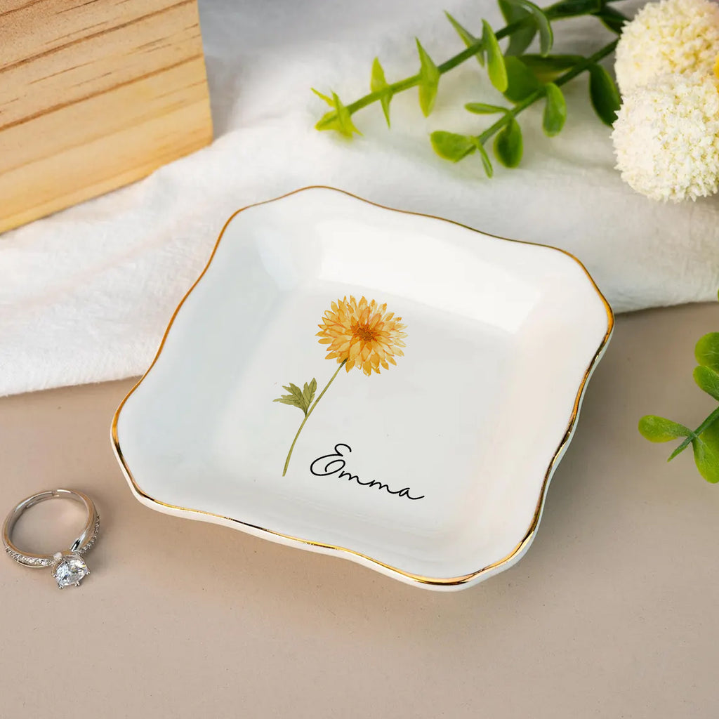 Decorative dish with a yellow flower design and the name 'Emma' on a beige surface.