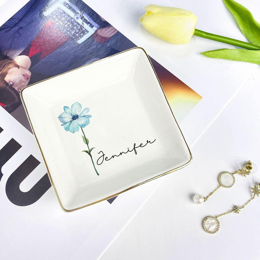 Jewelry dish with floral design and 'Jennifer' text, placed on a magazine with tulips and earrings.