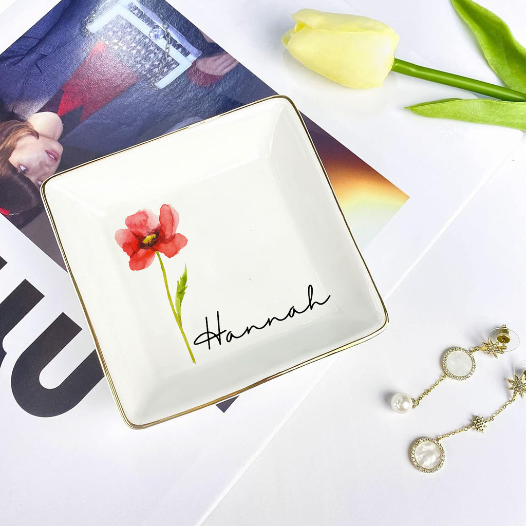 Jewelry dish with floral design and 'Hannah' text, placed on a magazine with tulips and earrings.